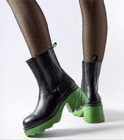 Black high-heel winter boots with vibrant green contrasting heel, worn with dotted tights, showcasing a modern stylish look.