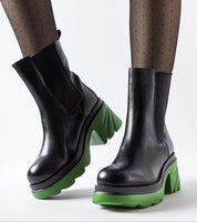 Black high-heel winter boots with green soles, showcasing a modern design with a bold block heel and slip-on style, ideal for cold weather.