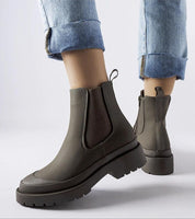 Pair of Varenta Weatherproof Platform Boots with zipper closure, designed for grip and style, worn with cuffed jeans.
