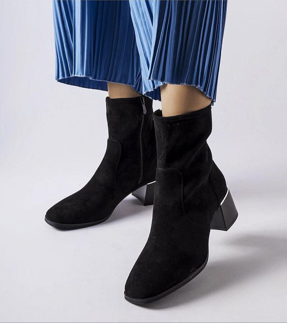 Soretta Perforated Zip-Up Boots in black eco-leather with flat 5 cm heel and blue pleated trousers, showcasing modern elegance and style.
