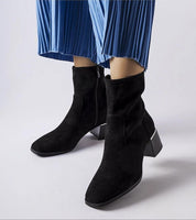Soretta Perforated Zip-Up Boots in black eco-leather with flat 5 cm heel and blue pleated trousers, showcasing modern elegance and style.