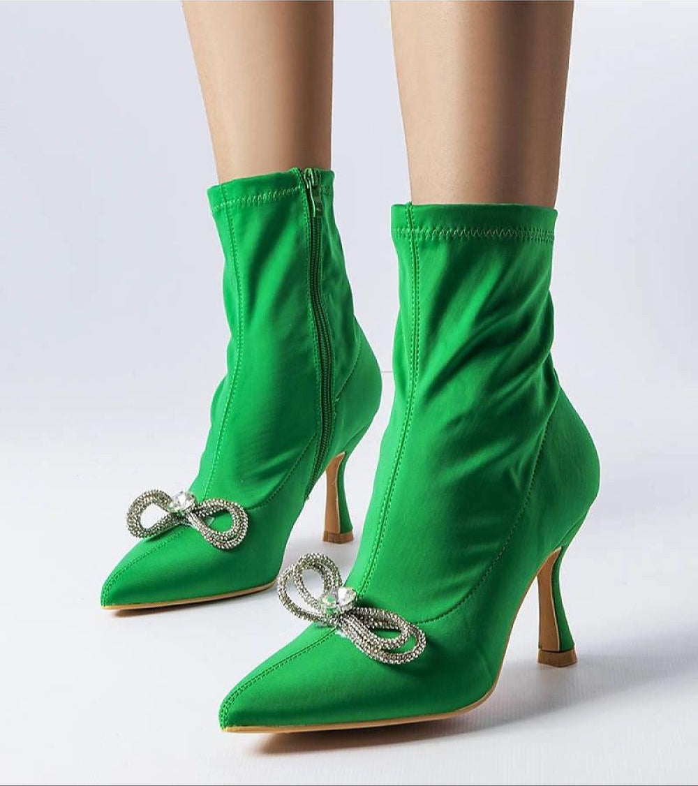 Green high-heel boots with rhinestone bow detail and side zipper, showcasing elegant design and style.