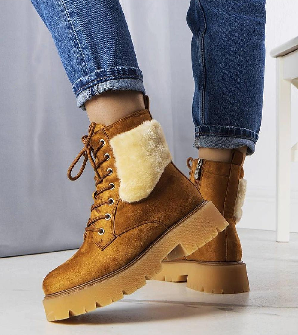 Brown fur-lined Arvenno winter boots paired with blue jeans on a white floor.