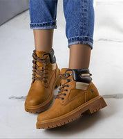 Person wearing brown leather trapper boots with fur lining, suitable for winter adventures; paired with blue jeans on a marble floor.