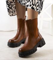 Brown Ferensa tall boots with side zip, eco leather upper, and black rubber sole, shown with black and white patterned skirt.