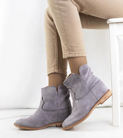 Woman wearing beige pants paired with Hunjet gray slip-on boots, displaying minimalist design and hidden 7.5 cm heel for style.