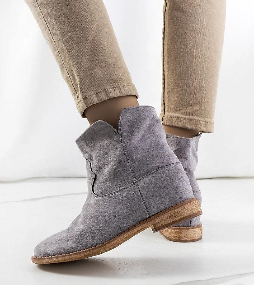 Gray slip-on boots with hidden heel, worn with beige pants, showing minimalist design and versatile style.