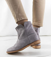 Gray slip-on boots with hidden heel, worn with beige pants, showing minimalist design and versatile style.