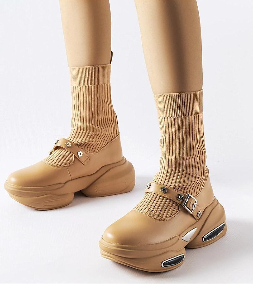 Beige stretch knit ankle boots with a sock-like design, buckle accents, and chunky soles, showcasing modern fashion versatility.