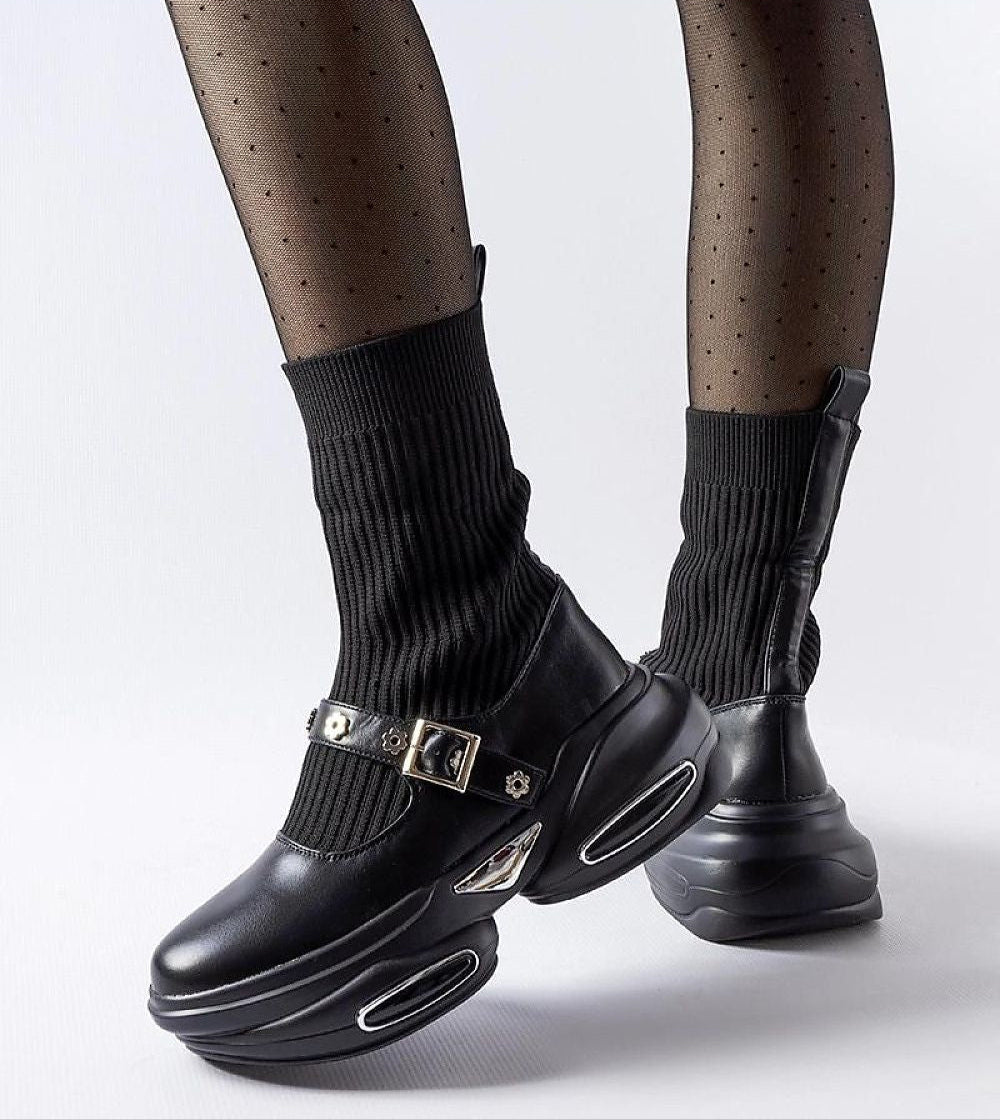 Black sock-like knit ankle boots with chunky platform, silver buckles, and sleek design showcased in stylish polka dot tights.