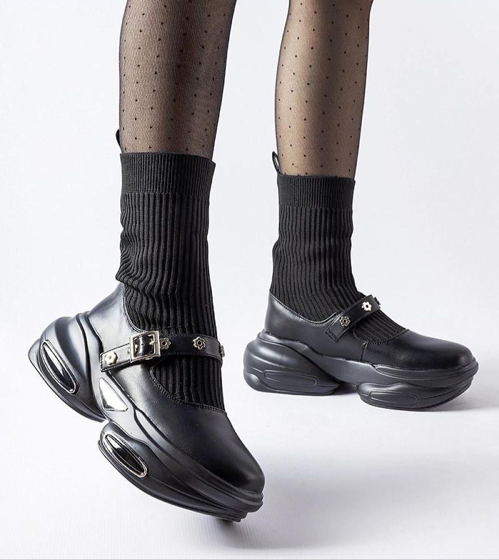 Stylish black platform shoes with ribbed socks, featuring edgy buckled straps and a unique sole design for a modern look.