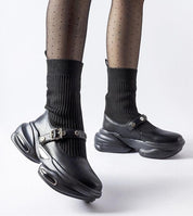 Stylish black platform shoes with ribbed socks, featuring edgy buckled straps and a unique sole design for a modern look.