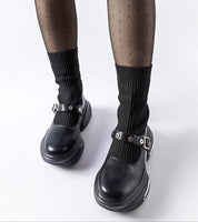 Black leather Mary Jane shoes with silver buckles paired with ribbed socks and polka dot stockings, showcasing a stylish ankle look.