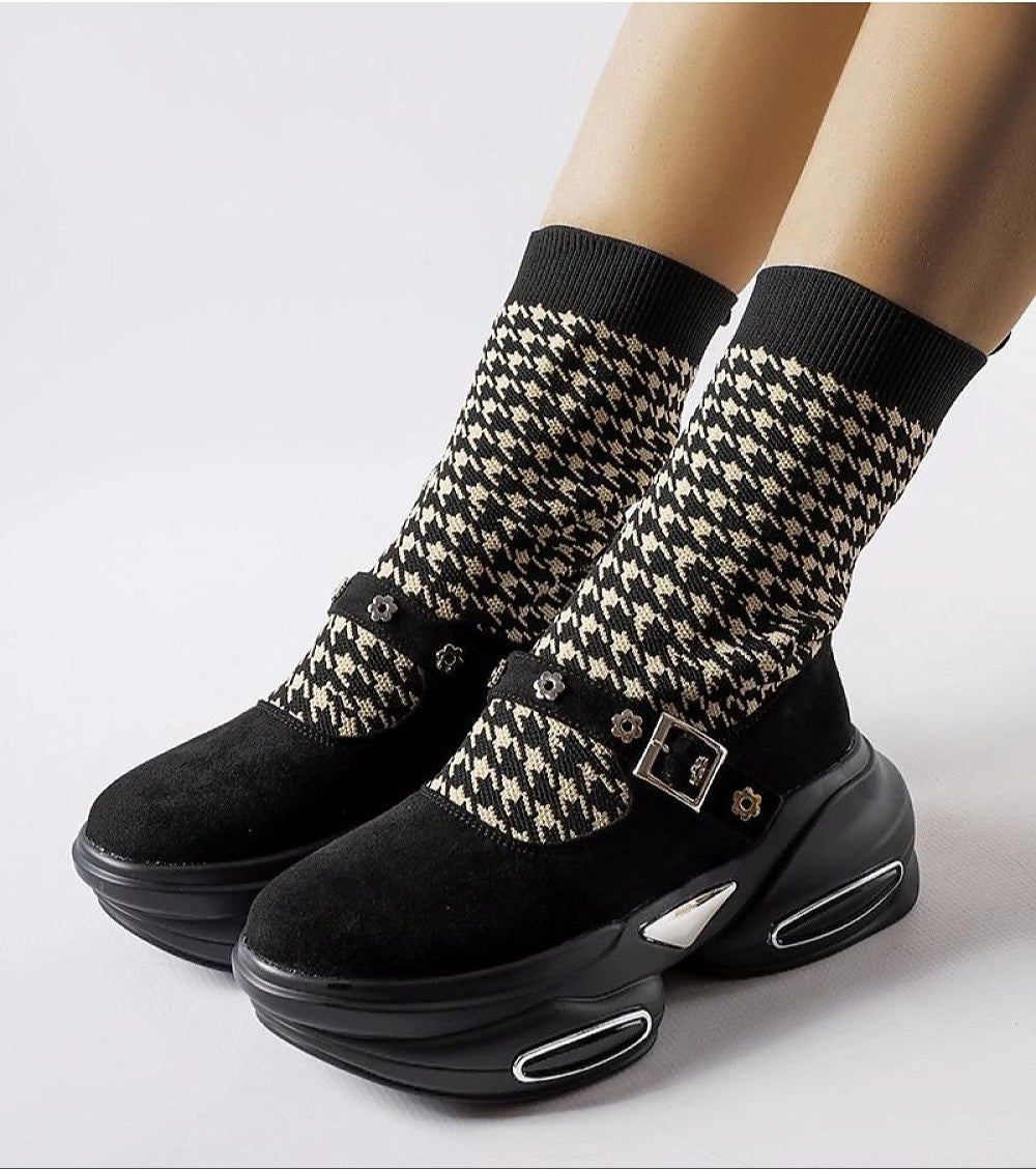 Women's black and beige stretch knit ankle boots with chunky sole and buckle detail on houndstooth pattern. Stylish and versatile footwear.