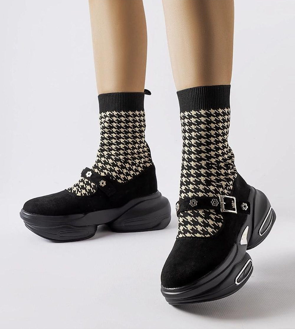 Chunky black platform shoes with houndstooth-print ankle socks and buckle detail, worn on light beige legs.