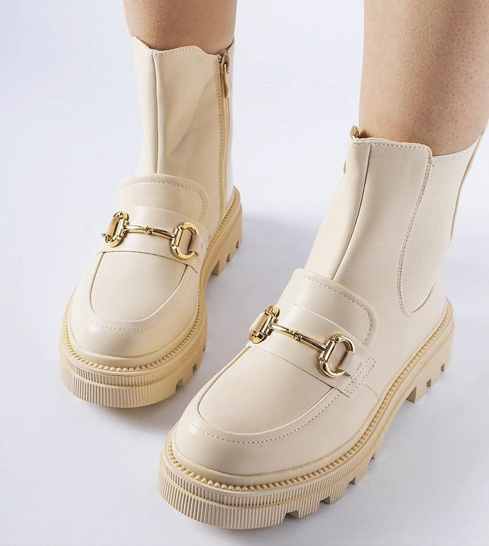 Beige leather boots with gold buckle details and chunky sole, showcasing the stylish design and zipper closure for easy wear.