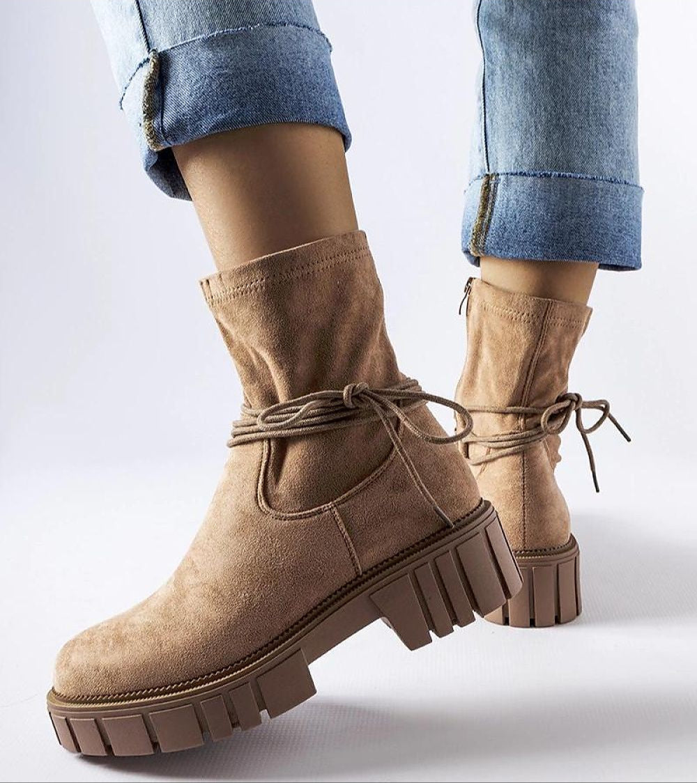 Woman wearing beige Veronea Zipped Bonded Boots with decorative lacing and durable rubber sole, paired with rolled-up jeans.