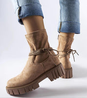 Woman wearing beige Veronea Zipped Bonded Boots with decorative lacing and durable rubber sole, paired with rolled-up jeans.