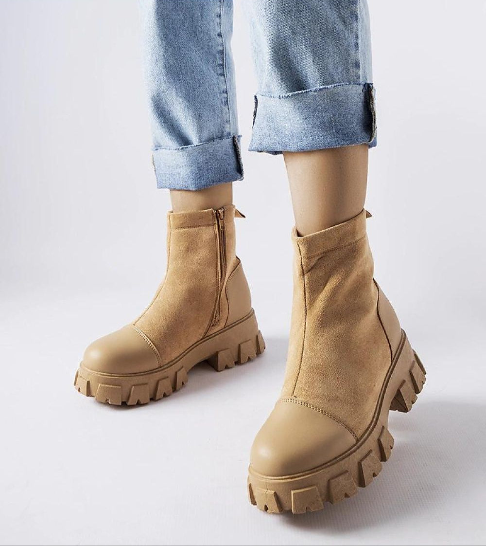 Beige suede platform boots with rugged sole and side zipper, worn with cuffed jeans, showcasing bold design and practical comfort.
