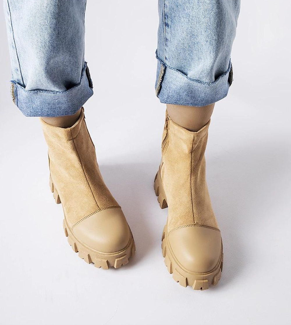 Beige suede platform boots with rugged rubber sole and rounded toe, styled with rolled-up denim jeans.