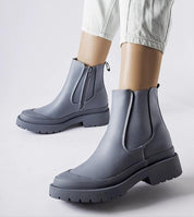 Gray Varenta Weatherproof Platform Boots with zipper closure and thick sole shown on person wearing white jeans.