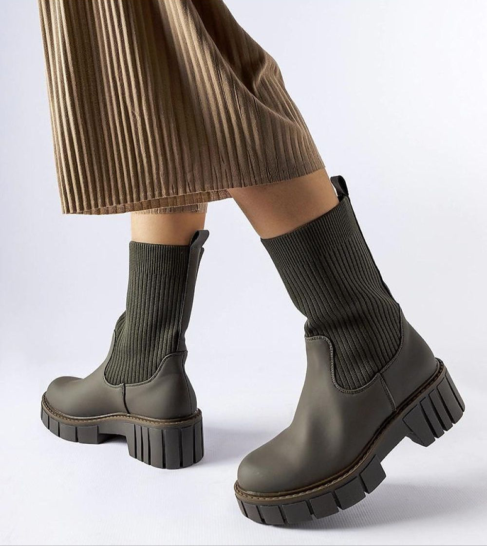 Model wearing Avidra Knit Platform Boots with stretch-knit upper, green sole, and pleated skirt for stylish everyday look.