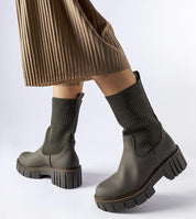 Model wearing Avidra Knit Platform Boots with stretch-knit upper, green sole, and pleated skirt for stylish everyday look.