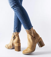 Woman wearing Artemisia Eco Leather Heel Boots with side cutouts, paired with distressed jeans, showcasing the bold beige design.
