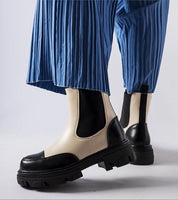 Albany Two-Tone Rubber Platform Boots in black and beige worn with blue pleated pants, showcasing minimalist design and 5 cm heel.
