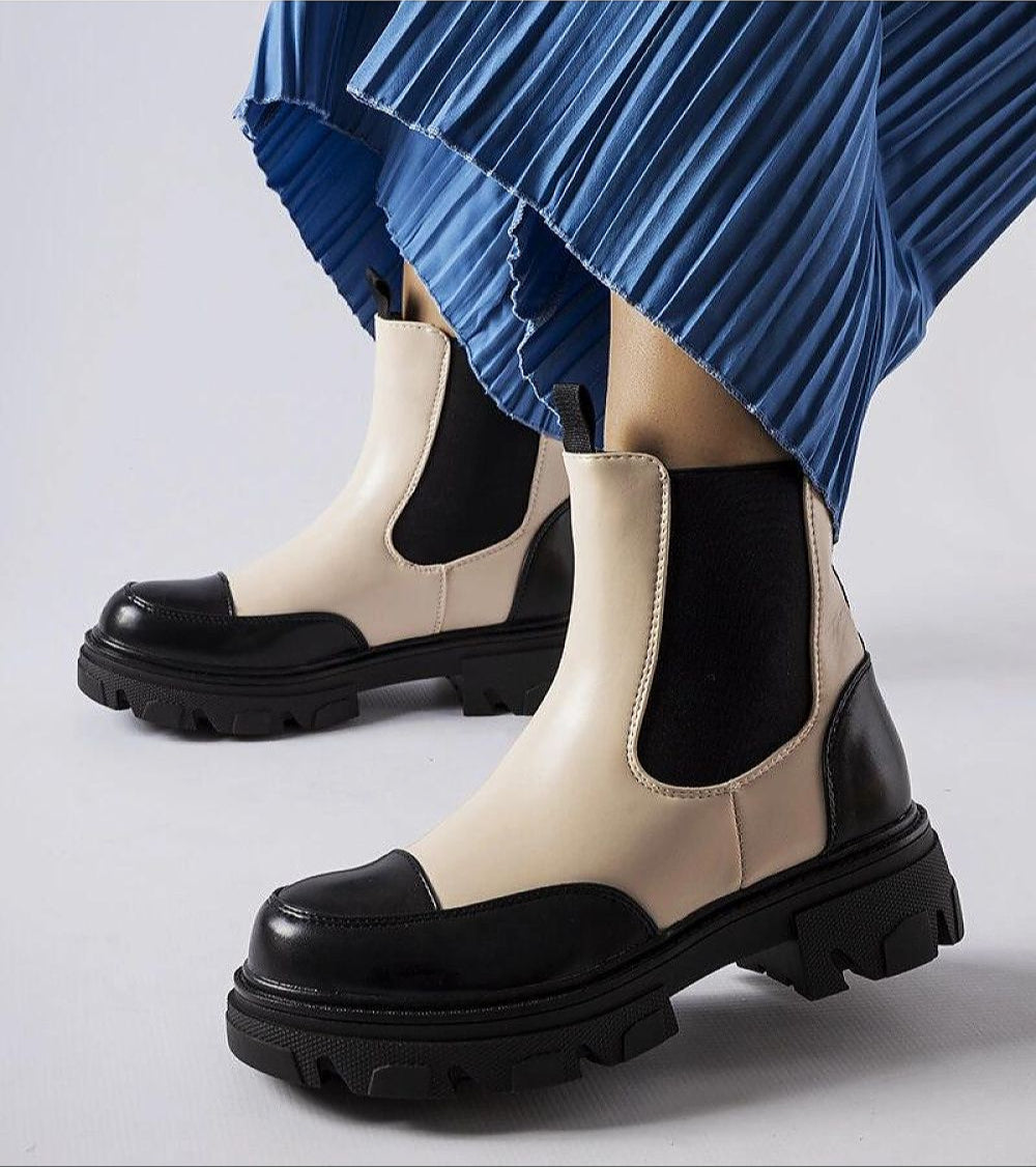 Albany Two-Tone Rubber Platform Boots in black and beige, worn with blue pleated skirt, showcasing durable design and minimalist style.