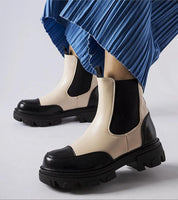 Albany Two-Tone Rubber Platform Boots in black and beige, worn with blue pleated skirt, showcasing durable design and minimalist style.