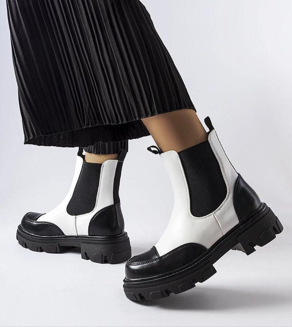 Fashionable Albany two-tone black and beige rubber platform boots worn with pleated skirt, showcasing minimalist design and weather-resistant eco leather.