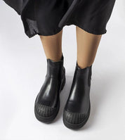 Matte black eco-suede slip-on bagger boots with rubber insets and platform heel, styled for urban comfort and stability.