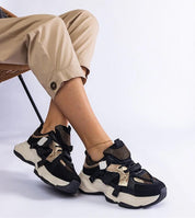 Person wearing black and gold Avessia Elevated Suede Accent Sneakers with sculpted soles and shimmering inserts.