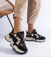 Woman wearing Avessia Elevated Suede Accent Sneakers with shimmering inserts and 6 cm platform, paired with beige pants.