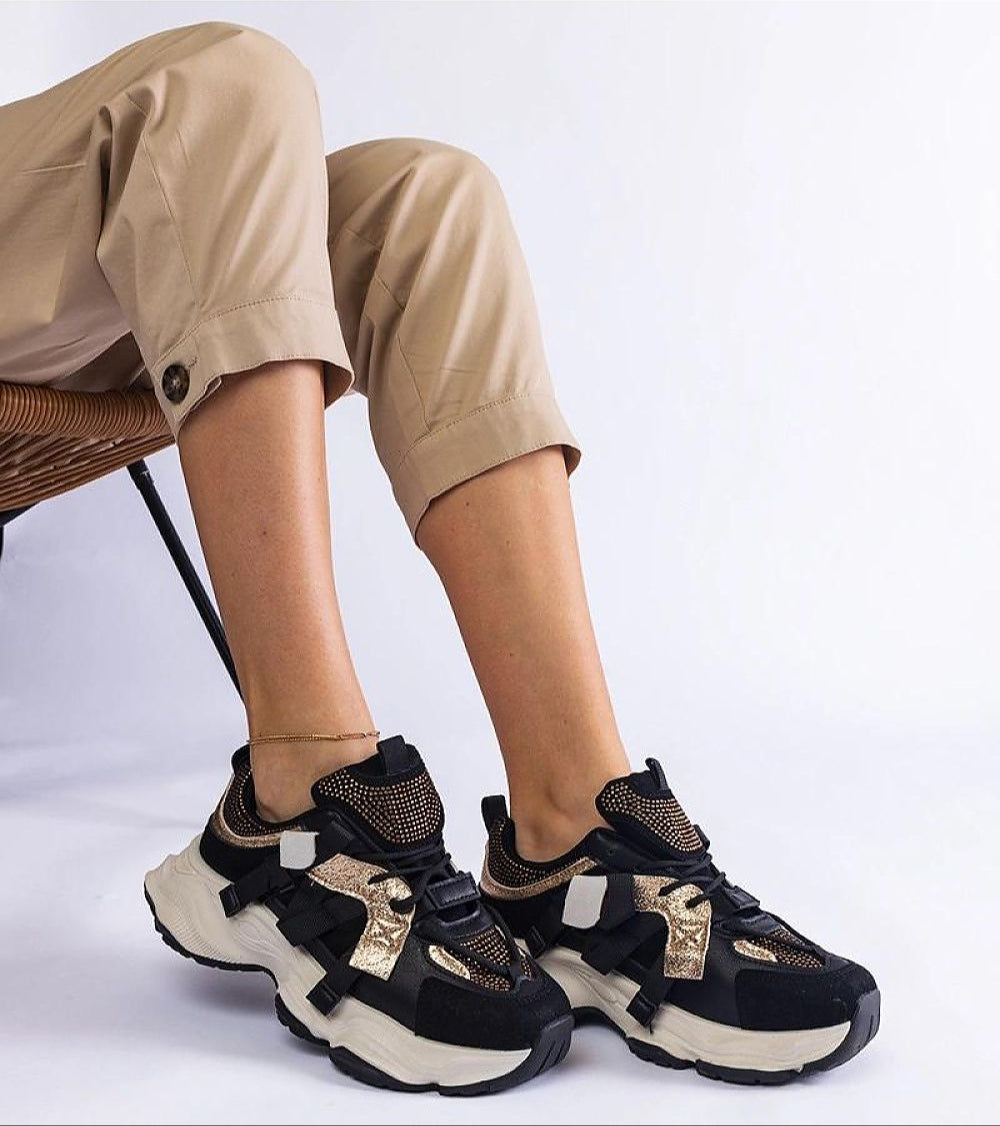 Woman wearing Avessia Elevated Suede Accent Sneakers with sculpted sole and shimmering inserts, styled with beige pants for a casual look.