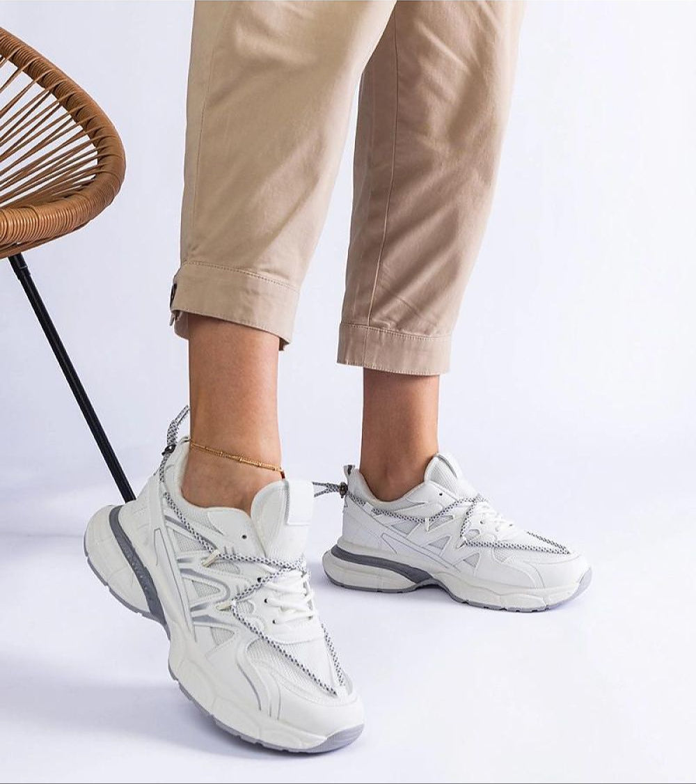 Person wearing Yndessa Sculpted Sole Lace Sneakers with beige pants, showcasing modern low-top design and eco leather material.