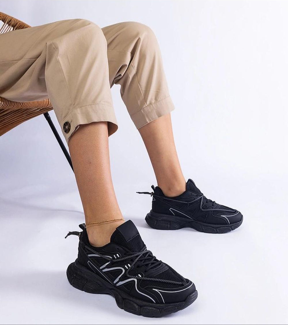 Woman wearing Yndessa Sculpted Sole Lace Sneakers in black, featuring a sleek design and sculpted sole for modern style and comfort.