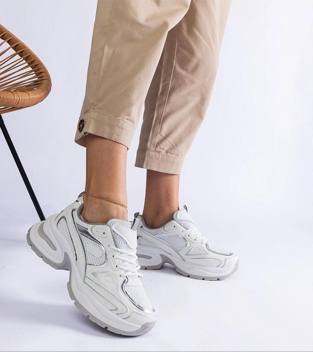 Woman wearing Elphira chunky sole white sneakers with beige pants, showcasing comfortable gray rubber platform and modern design.