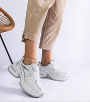 Woman wearing Elphira chunky sole white sneakers with beige pants, showcasing comfortable gray rubber platform and modern design.