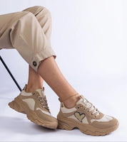 Orevia heart-detailed brown sneakers with platform design and eco leather, featuring heart-shaped accent on sides, worn with beige pants.