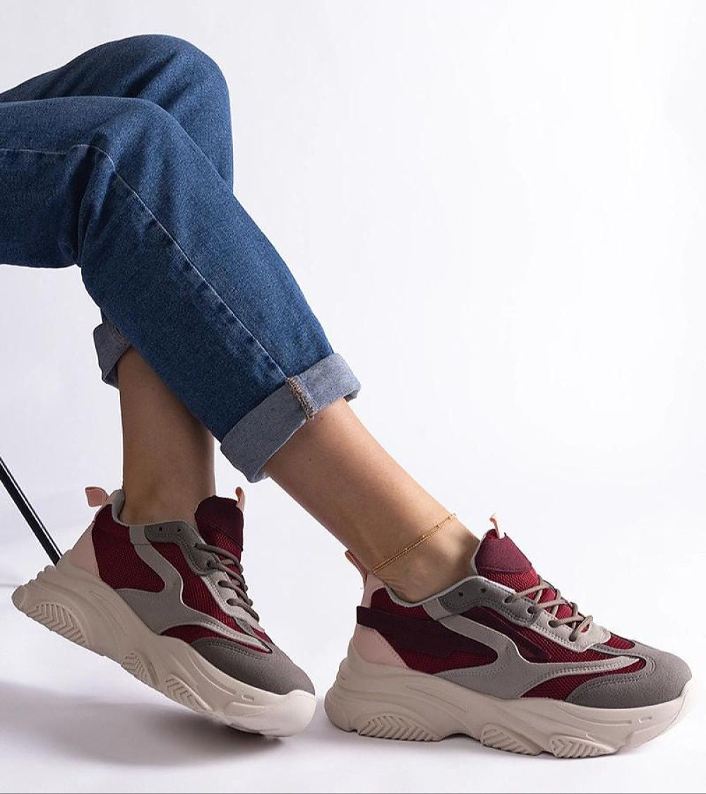 Person wearing Cordevia Burgundy-Grey Urban Sneakers with elevated 5.5 cm sole, complementing blue jeans for a stylish casual look.