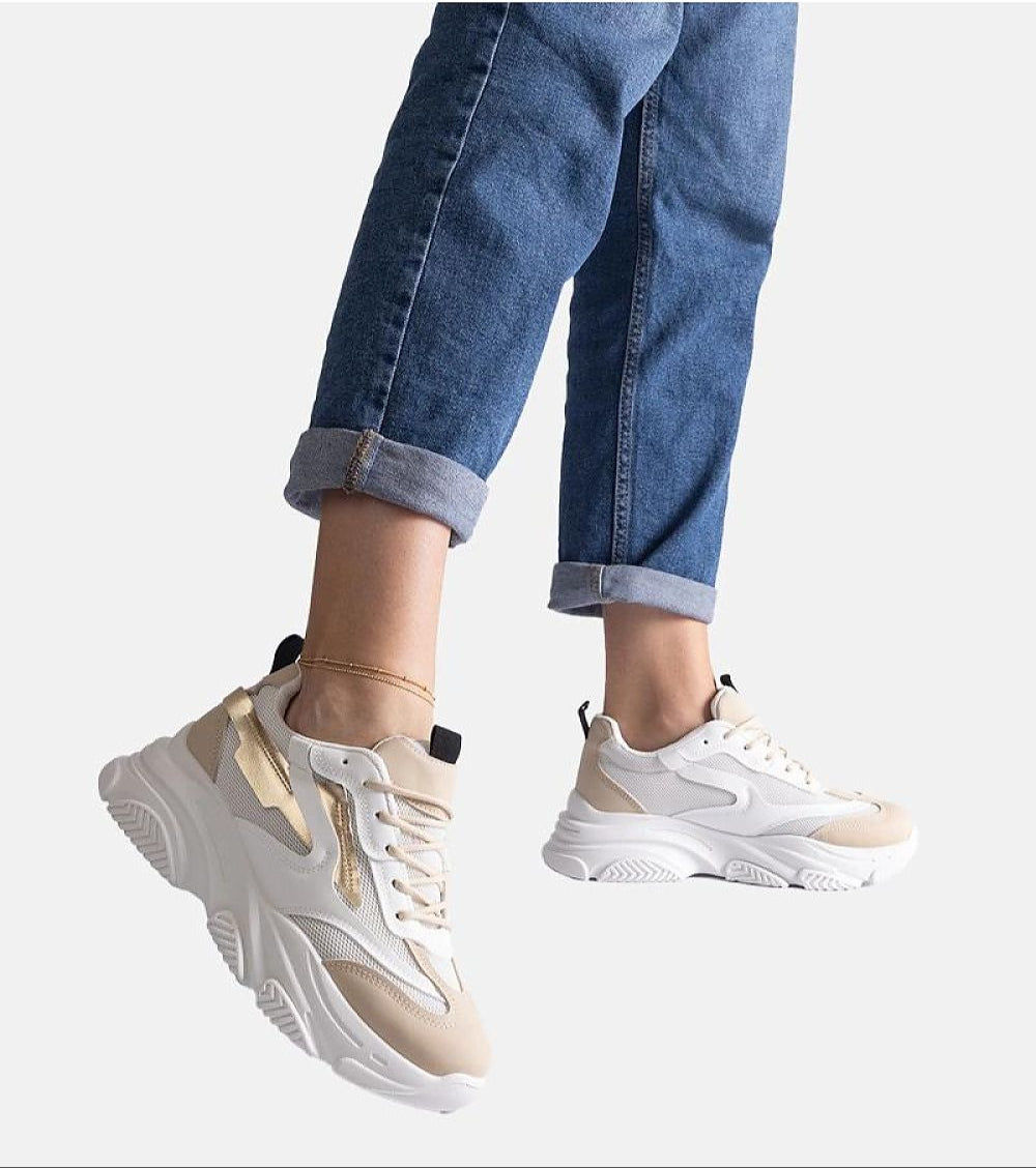 Stylish beige and white chunky sneakers paired with rolled-up denim jeans.