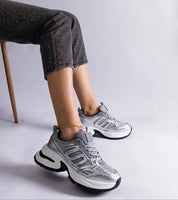 Person wearing Lunvera Metallic Sport Style Sneakers with silver upper and black sole, showcasing sleek, athletic design and eco leather.