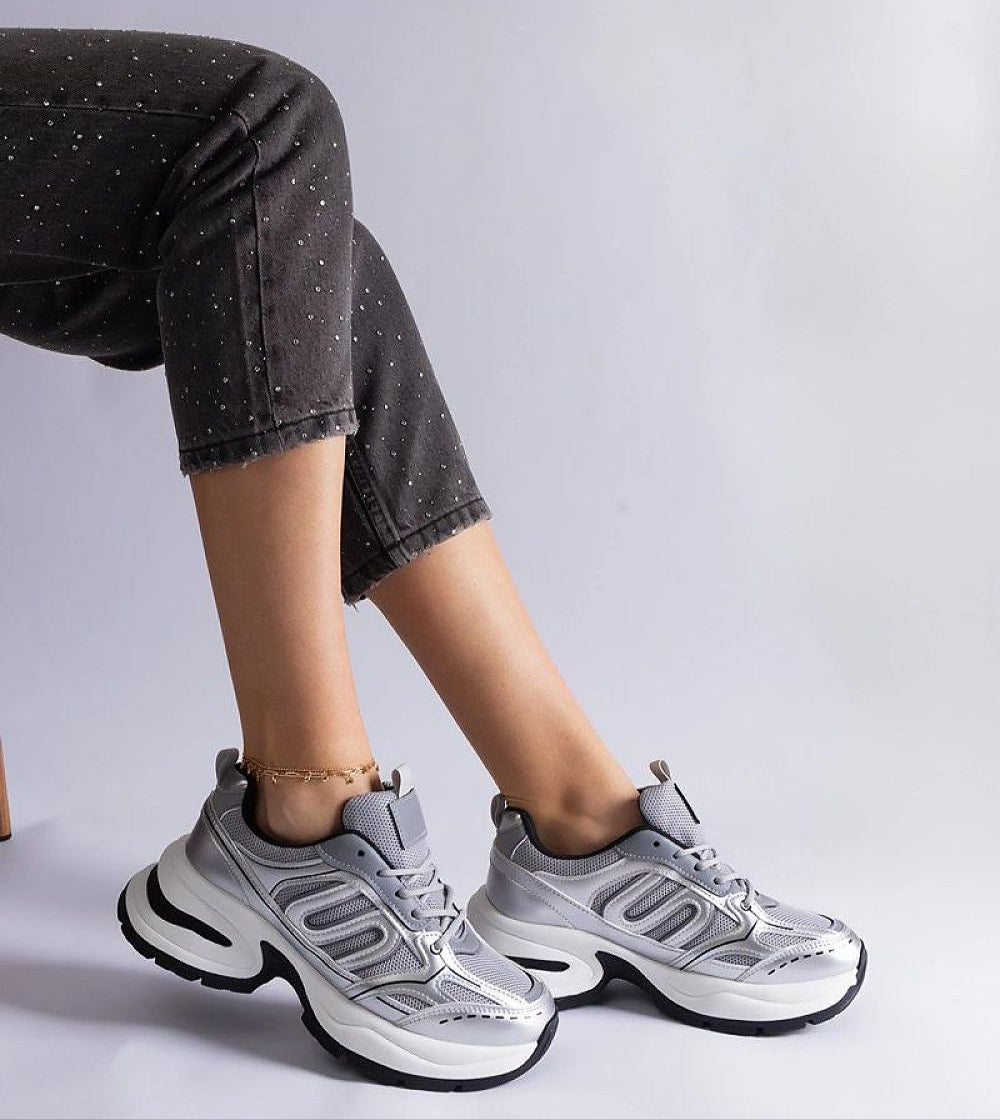 Lunvera metallic sport-style sneakers with silver upper and black sole, worn with dark jeans. Ideal for urban and athletic wear.