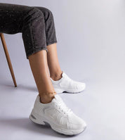 Person sitting wearing Melvyna White Motion Sneakers with eco leather upper and flexible gray sole, demonstrating comfort and style.