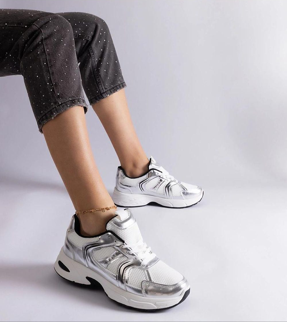 Person wearing Melvyna White Motion Sneakers with eco leather uppers and flexible gray soles, showcasing stylish and sporty footwear.