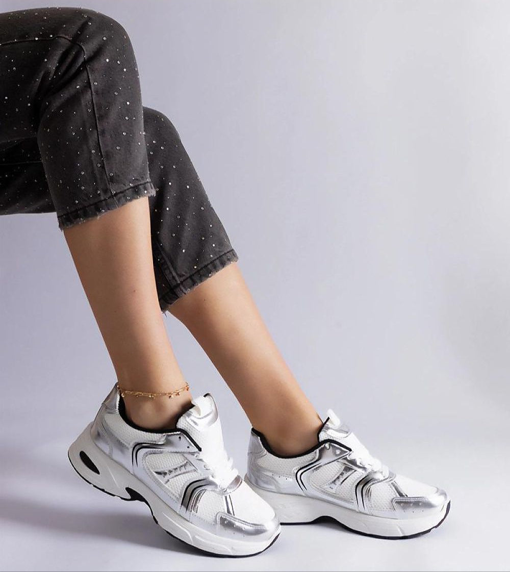 Woman wearing Melvyna White Motion Sneakers with eco leather upper and lace-up design paired with speckled black pants.