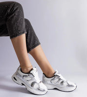Woman wearing Melvyna White Motion Sneakers with eco leather upper and lace-up design paired with speckled black pants.