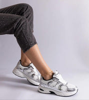 Person wearing white motion sneakers with black speckled pants, showcasing a stylish and casual fashion look.